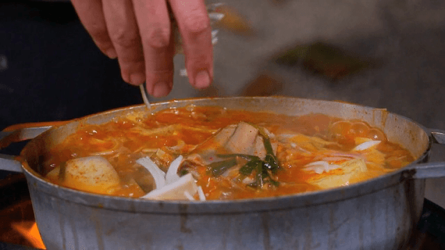 냄비에서 끓고 있는 찌개에 양파 넣기
