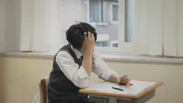 창가에서 시험을 보며 머리를 긁는 학생