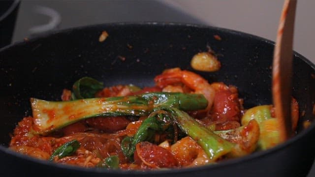 팬에서 청경채와 당면, 새우를 볶는 모습