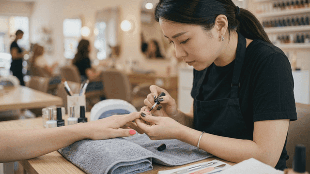 Nail artist carefully applying nail polish.