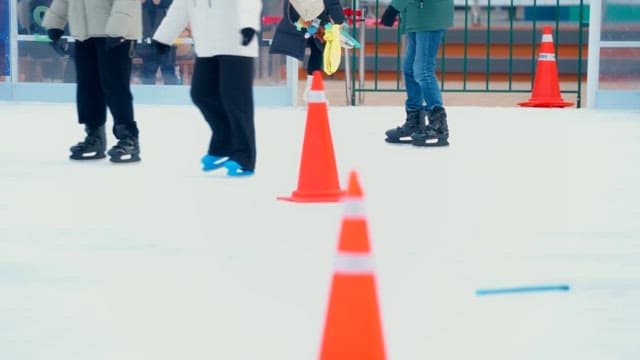 People ice skating on a rink with cones