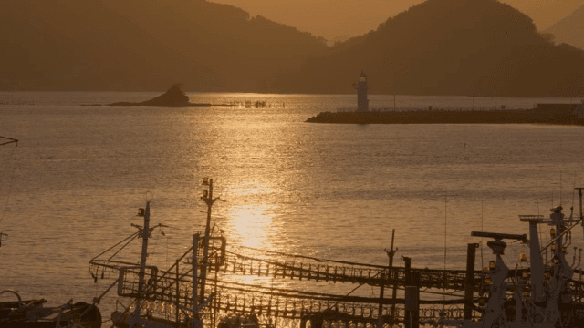 해질녘 바다의 등대와 어선들
