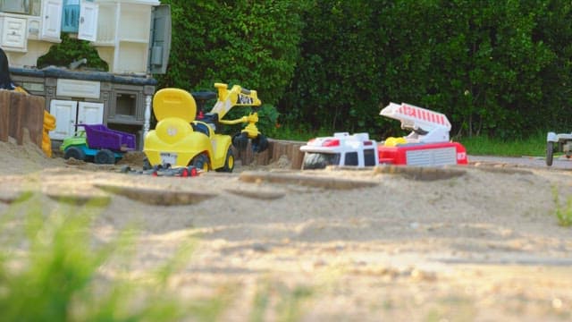 뒷마당 정원 근처 모래밭에 흩어진 장난감