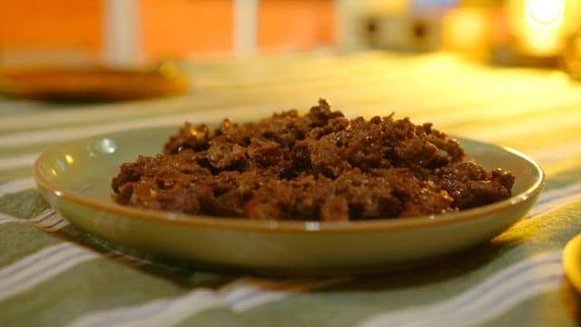 A plate of bulgogi topped with green onions on an indoor table