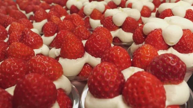 Strawberry desserts being decorated with whipped cream