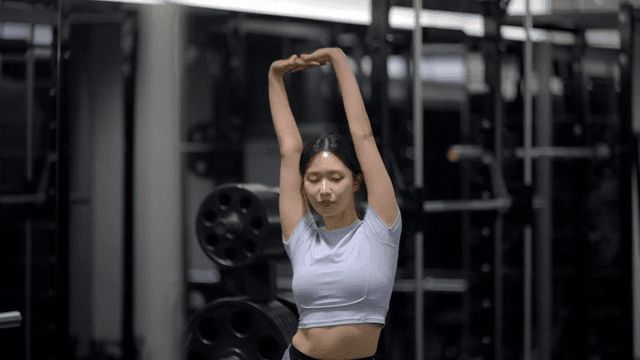 Stretching arm extended by young woman in gym