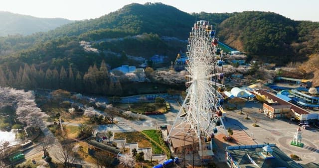 Amusement park scenery with Ferris wheel and lush hills