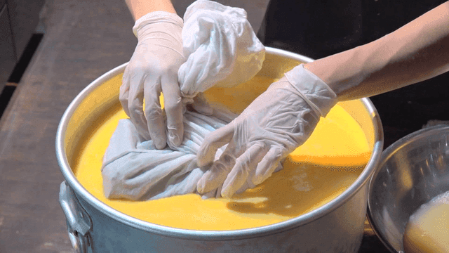 Chef dipping cloth pouch into pot filled with egg mixture