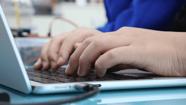 Hands typing on a laptop keyboard