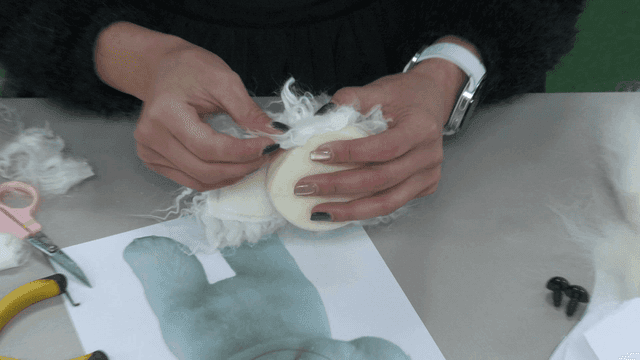 Hands crafting a fluffy toy with tools