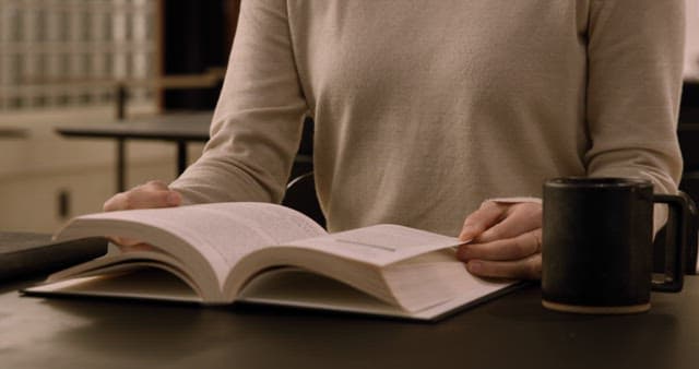 Person Reading a Book at a Desk with Coffee