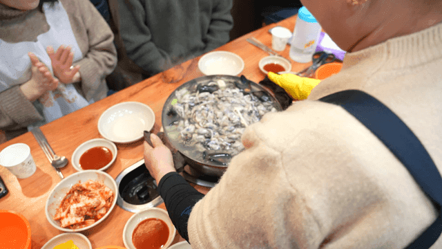Woman serving oyster kalguksu at restaurant