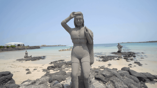 Statue of female diver on beach on clear day