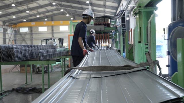 Worker handling metal sheets in a factory