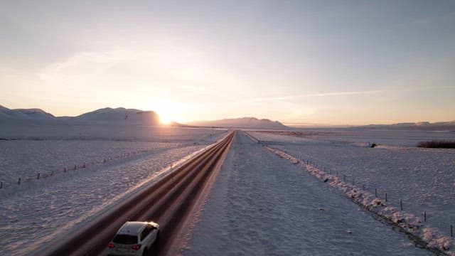 Car driving on a snowy road at sunrise