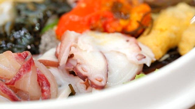 Picking up octopus in cold raw fish soup using chopsticks