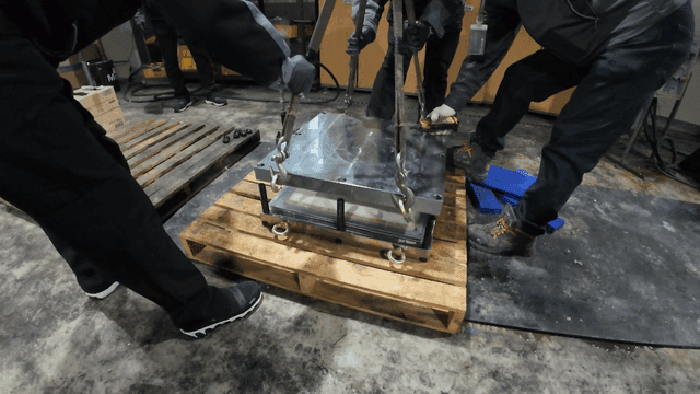 Workers lifting metal molds in factory