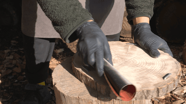 야외에서 나무 통을 사포질하는 모습