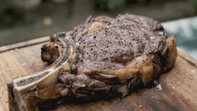 Well-grilled steak placed on wooden cutting board