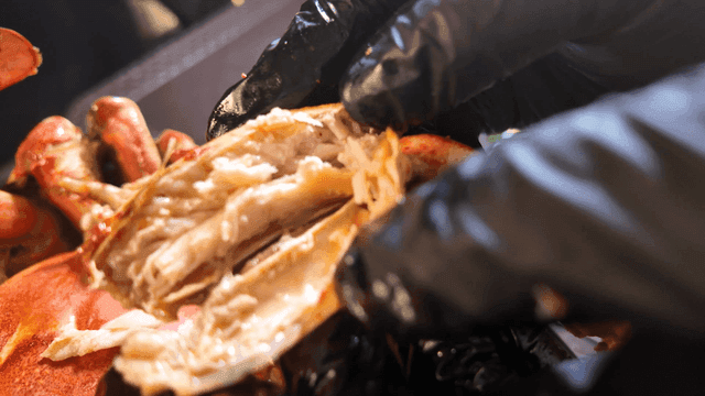 Glove-wearing hands extracting crab meat for yellow crab soup