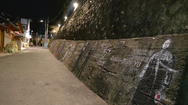 Quiet alley in a Hanok village with murals depicting great Korean figures at night