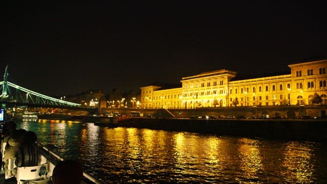 조명이 켜진 건물과 다리를 지나는 크루즈 여행