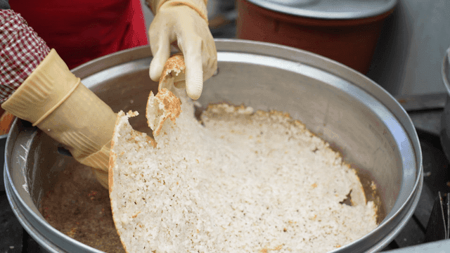 Person scraping burnt rice from pot