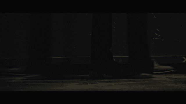 Shoes of person walking down dark hallway