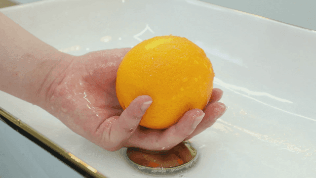 흐르는 물에 오렌지를 씻는 모습