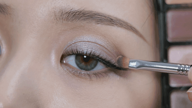 Eyes of woman applying eyeshadow with brush