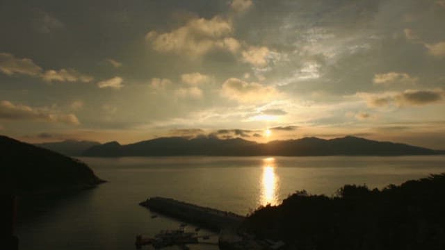 일몰에서 저녁으로 넘어가는 하늘 아래 고요한 바다와 산과 바다