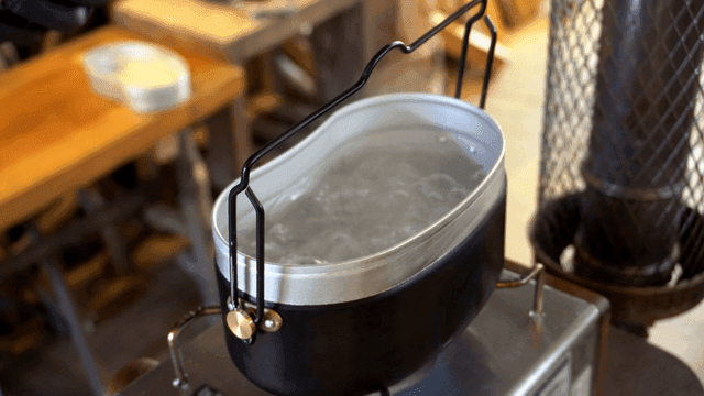 Ramen noodles being placed into an army pot indoors