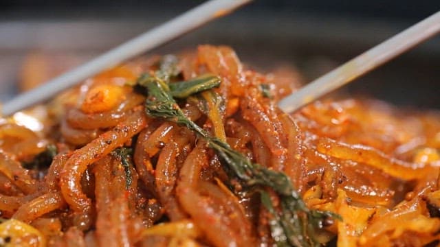 Chopstickful of glass noodles in stir-fried gopchang with vegetables