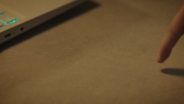 테이블 위 노트북 키보드를 장난스럽게 누르는 손가락