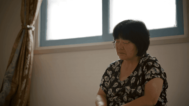 An elderly woman sitting quietly indoors