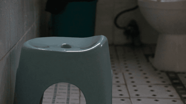 Bathroom with plastic bath chair and toilet