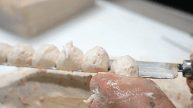 Fish cake dough rising in circle on knife
