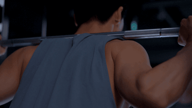 헬스장에서 어깨에 무게를 지고 스쿼트를 하는 남자