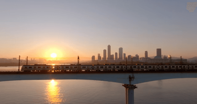 일몰 시간대에 강 위의 다리를 건너는 기차