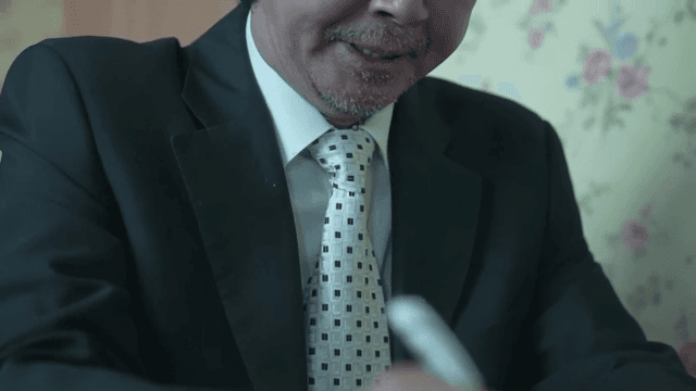 책상에서 메모를 하는 정장 입은 남자