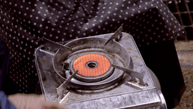 People warming their hands on lit gas burner