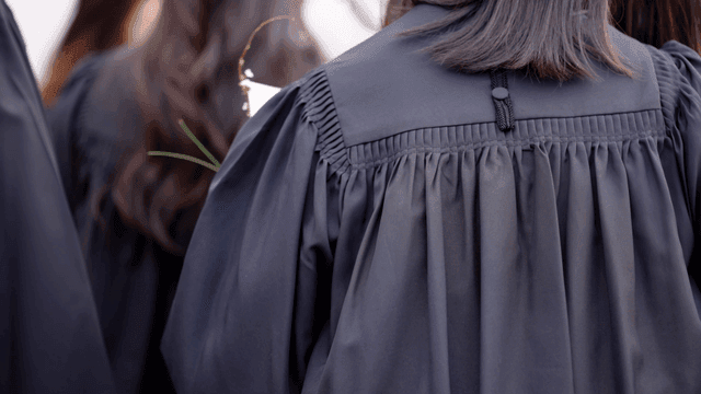 Graduates in black gowns holding flowers