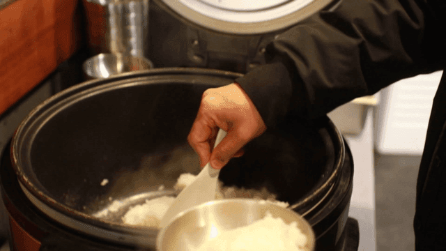 Serving freshly cooked rice from a cooker