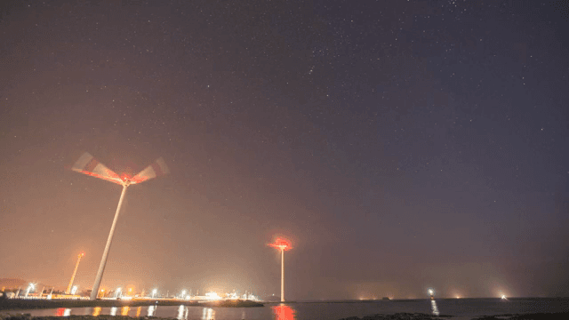 Wind turbines spinning under a starry sky