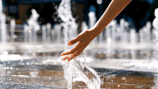 Hands touching water in fountain