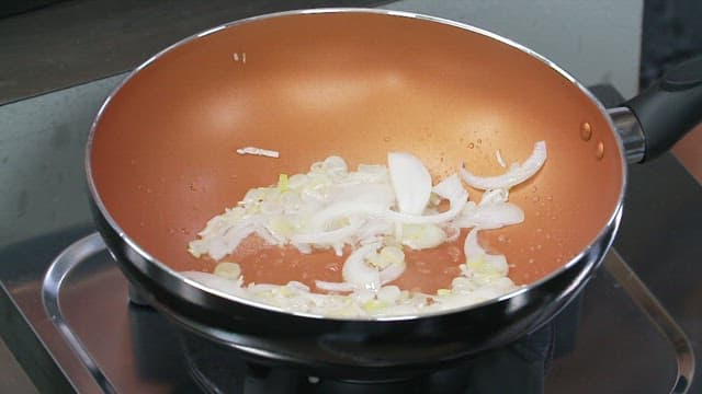 Onions and bamboo shoots being stir-fried in a pan