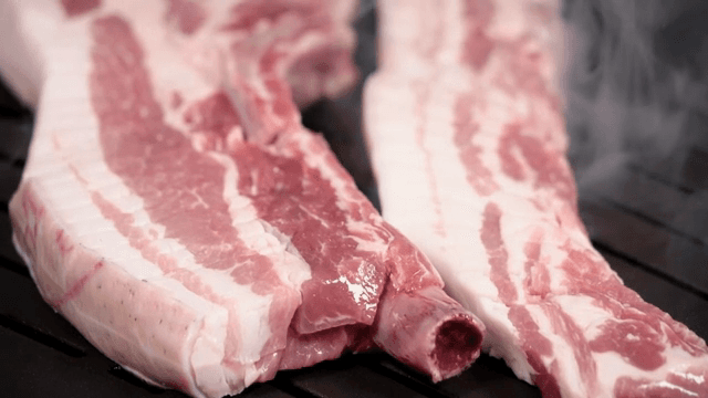 Raw pork belly slices on a grill