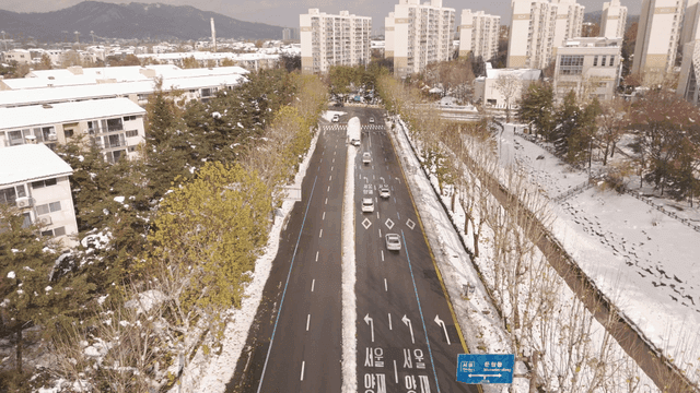 Snow-covered city road with moving cars