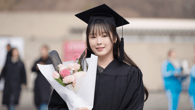Smiling graduate holding bouquet of flowers