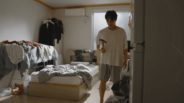 Man in a messy room holding a hammer